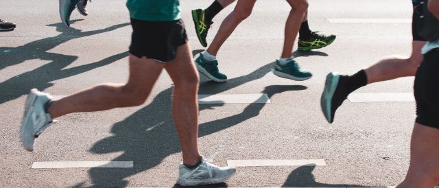 Läufer in sommerlicher Sportbekleidung die auf einer Strasse joggen und die vom Bauchnabel bis zum Fuss sichtbar sind.