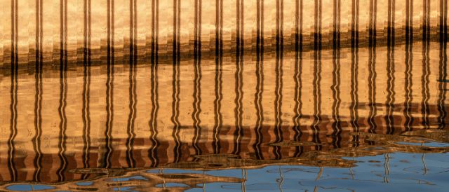 Fotografie von Donata Ettlin die in eine Spiegelung im Rhein zeigt. Es ist eine golgen-leuchtende Hafenmauer zu sehen.