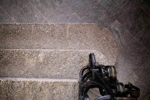 Treppenstufen aus Stein und Fuss eines Schmiedeeisernen Treppengeländers in schwarz