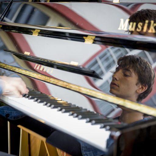 Nahaufnahme Musikfestival Em Bebbi sy Jazz: Junger Mann spielt Klavier, darin spiegelt sich sein Gesicht und die Häuser